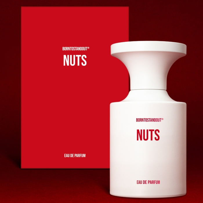 BORNTOSTANDOUT - Nuts Parfümflakon in weiß mit klarer Form und roter Schrift auf rotem Hintergrund