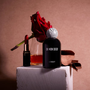 L'Objet - Oh Mon Dieu! Parfumflakon in tiefschwarzem Glas mit markantem weiß-rissigem Verschluss und roter Rose elegant arrangiert