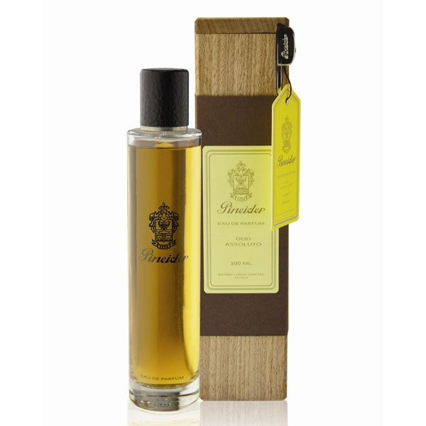Pineider - Oud Assoluto schlanker Parfumflakon mit schwarzem Verschluss und Holzbox mit gelbem Etikett auf weißem Hintergrund