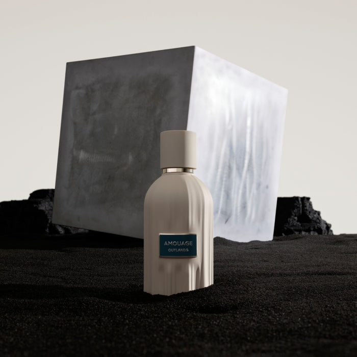 Amouage - Essences Collection - Outlands zeigt cremefarbenen Flakon mit blauem Label vor abstraktem kubischem Hintergrund