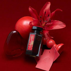 L'Artisan Parfumeur - La Collection - Passage d'Enfer Extrême Flakon mit roter Lilie und dekorativen roten Objekten auf rotem Hintergrund