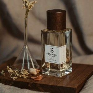 Botanicae - Patio Parfumflakon mit klarem Glas und dunkelbraunem Holzverschluss auf Holzunterlage mit getrockneten Blumen