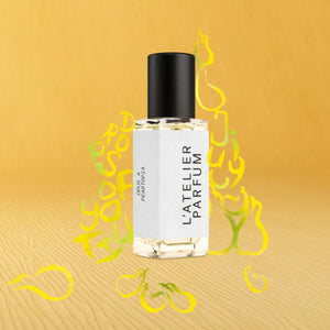 L'Atelier Parfum - Opus 4 - Peartopia Flakon mit schwarzem Verschluss und grafischen Birnen auf gelbem Holzuntergrund