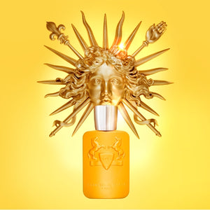Parfums de Marly - Perseus oranger Flakon mit erhabenem Pferdemotiv vor goldener Sonnenskulptur auf gelbem Hintergrund