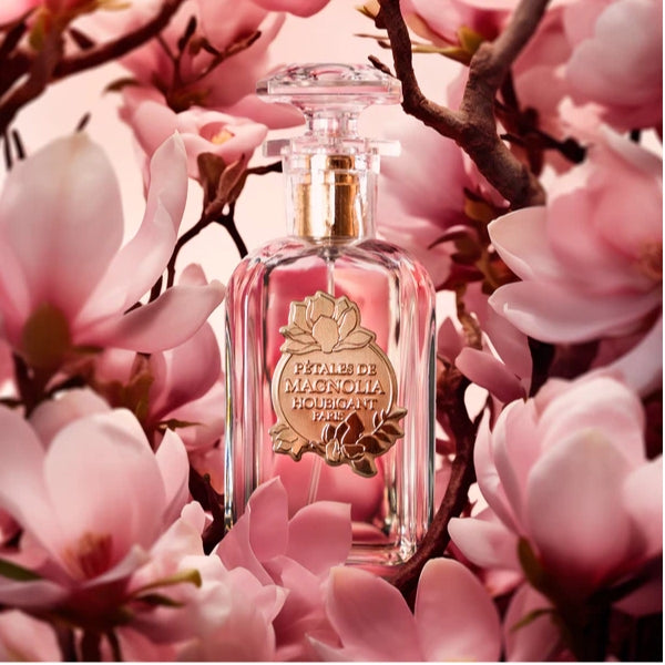 Houbigant - Pétales de Magnolia Flakon mit goldenem Emblem umgeben von zarten Magnolienblüten in sanften Rosa- und Pinktönen
