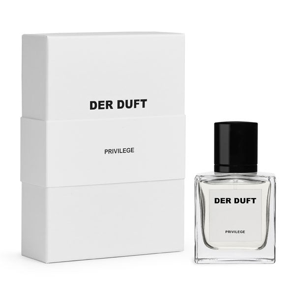 DER DUFT - Privilege Parfum im klaren Glasflakon mit schwarzem Verschluss neben schlicht weißer Verpackung