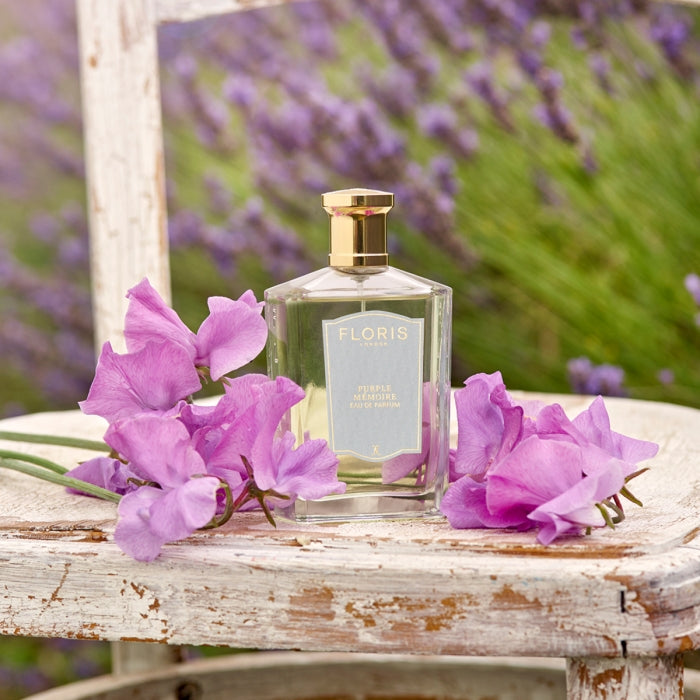 Floris - Purple Mémoire Parfumflakon auf verwittertem Holzstuhl umgeben von zarten lila Blüten und Lavendel im Hintergrund