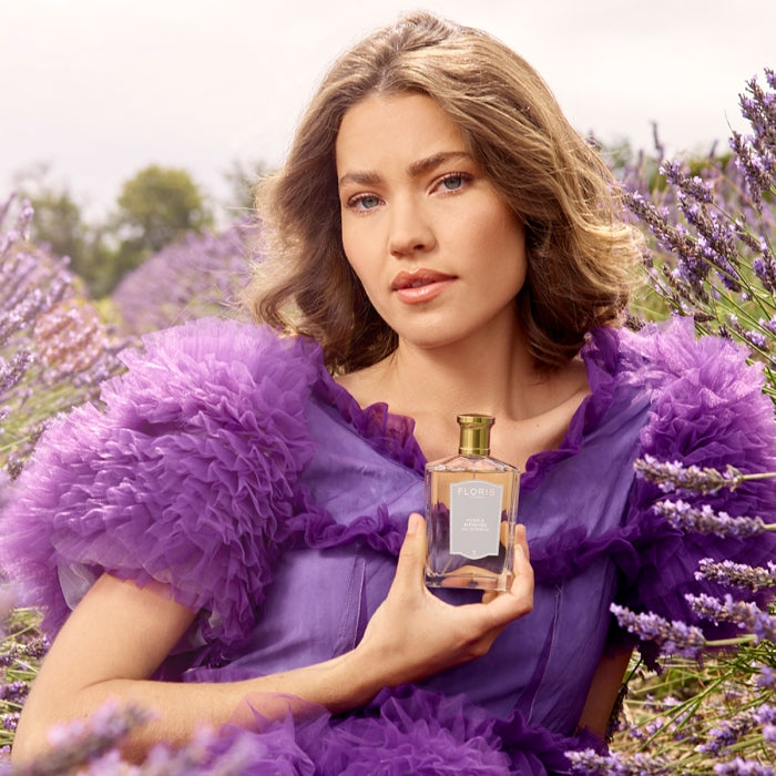 Floris - Purple Mémoire Flakon wird von Frau in lila Kleid umgeben von Lavendelfeld gehalten