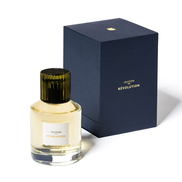 Trudon - Révolution Parfumflakon mit dunkelgrünem Deckel und goldener Flüssigkeit neben edler dunkelblauer Verpackung