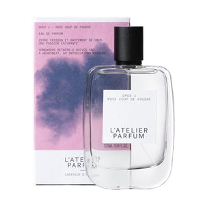 L'Atelier Parfum - Opus 1 - Rose Coup de Foudre Flakon vor zartem rosa und blauem Hintergrund mit elegantem Design