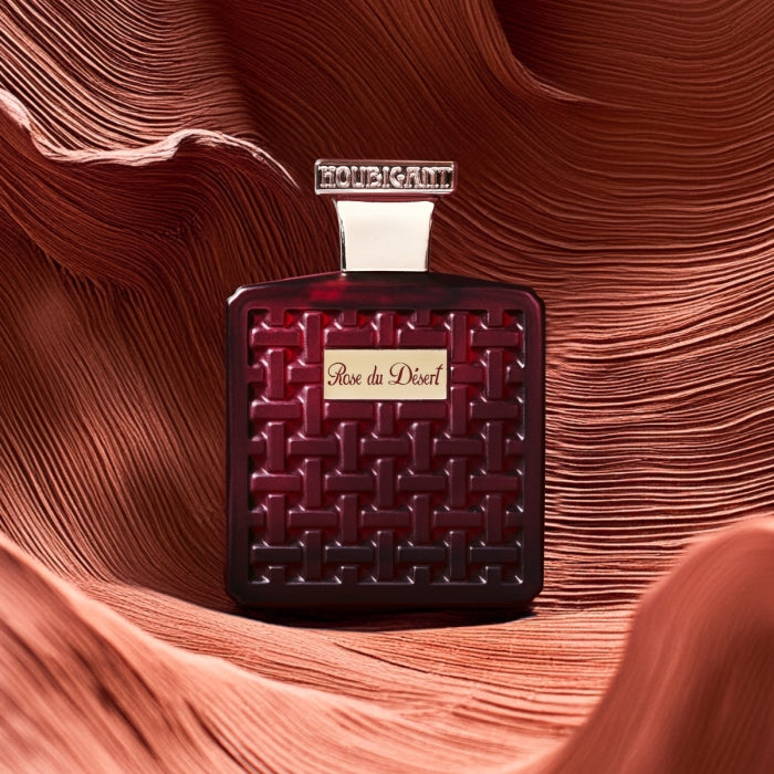 Houbigant - Collection les Ambres - Rose du Desert Parfumflakon in tiefrotem Design mit geprägtem Muster vor Wüstenhintergrund