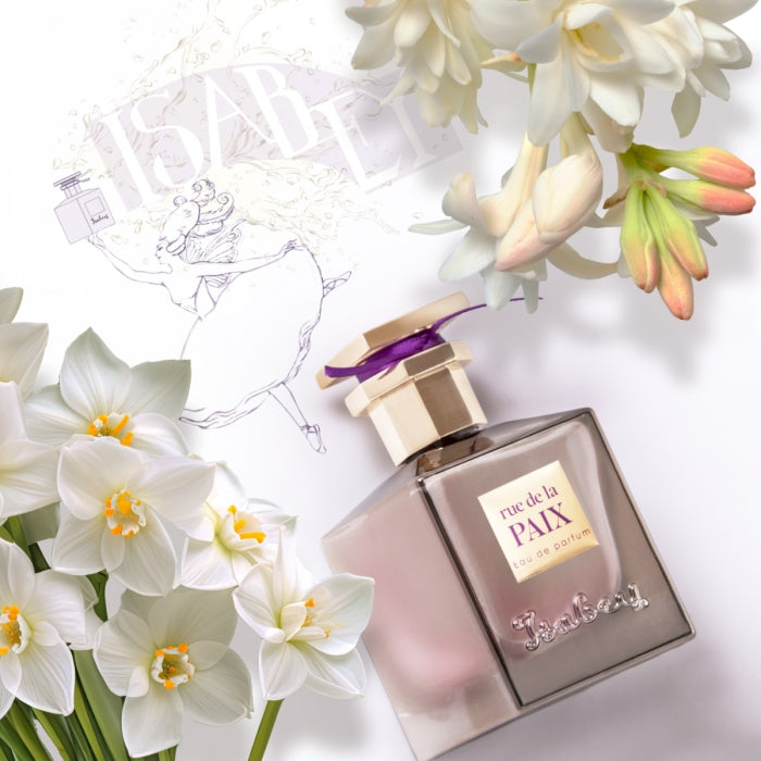 Isabey - Rue de la Paix Parfumflakon mit cremefarbenem Verschluss und violettem Akzent neben weißen Blüten auf hellem Hintergrund