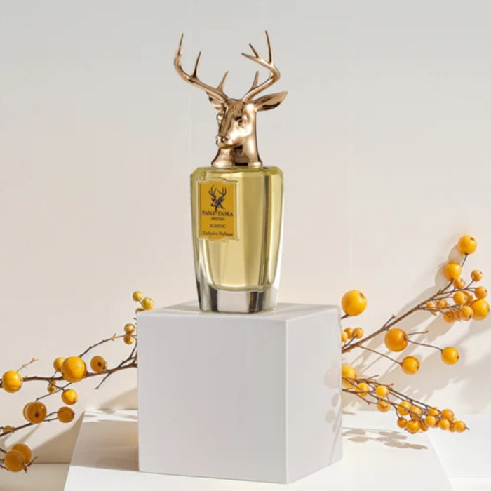 Pana Dora Sweden - Scandic Parfumflakon mit goldenem Hirschkopf auf weißem Podest vor gelben Beerenzweigen