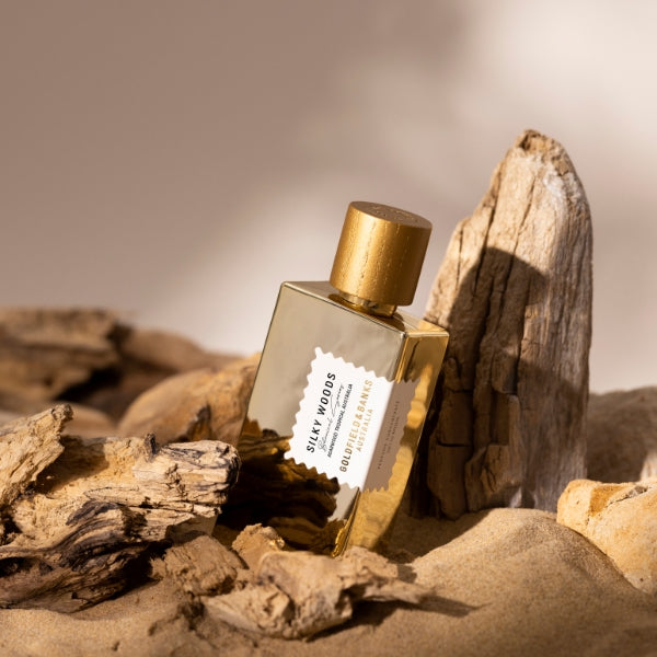Goldfield & Banks - Botanical Series - Silky Woods Elixir Parfumflakon in goldfarbenem Design zwischen Holzstücken und Sand