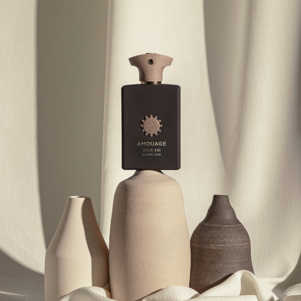 Amouage - Library Collection - Opus XIII - Silver Oud Flakon in mattschwarzem Design mit beigem Verschluss vor hellem Stoffhintergrund