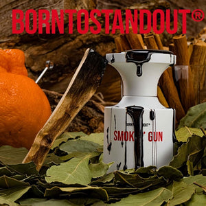 BORNTOSTANDOUT - Smokin' Gun Parfumflakon mit schwarzem Tropfen-Design vor natürlicher Holz- und Blattkulisse