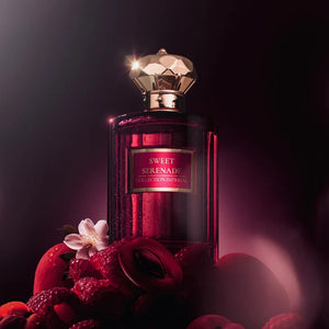 Imperial Parfums - Sweet Serenade purpurroter Flakon mit goldenem Verschluss umgeben von roten Früchten und zartem Blütenarrangement
