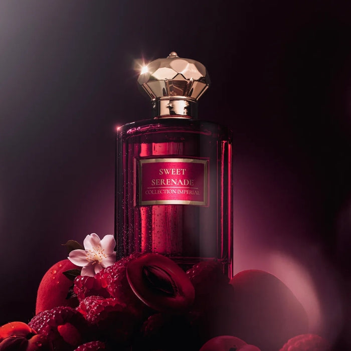Imperial Parfums - Sweet Serenade purpurroter Flakon mit goldenem Verschluss umgeben von roten Früchten und zartem Blütenarrangement