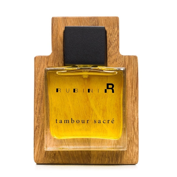 Rubini - Tambour Sacré Parfumflakon mit goldenem Duftöl und schwarzem Verschluss auf Holzrahmen vor weißem Hintergrund