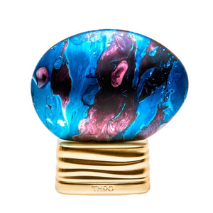 THoO - The Time Flakon mit blau-violett marmorierter Oberfläche auf welligem goldfarbenem Sockel vor weißem Hintergrund