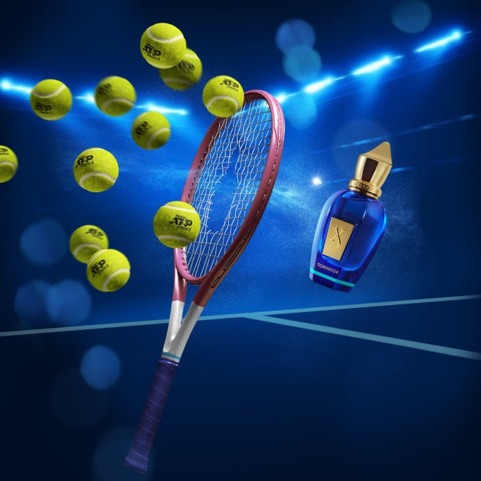 Xerjoff - Join The Club - Torino 24 Parfumflakon neben Tennis­racket und mehreren Tennisbällen auf blauem Spielfeld
