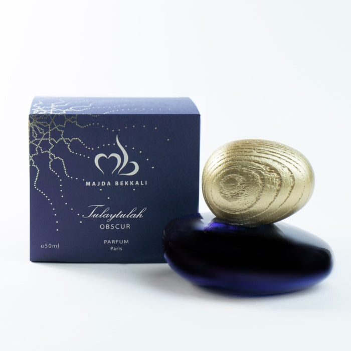Majda Bekkali - Tulaytulah Obscur Parfumflakon in tiefblauem Glas mit goldenem, ovalem Verschluss neben passender Verpackung