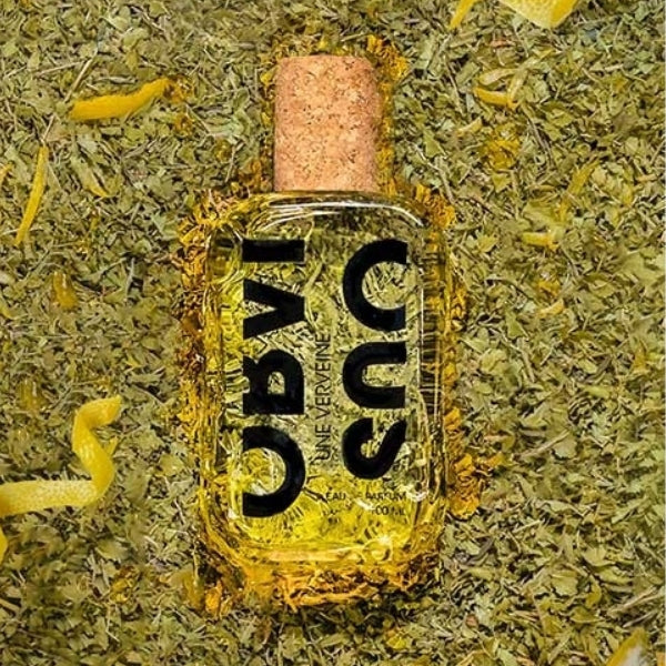 Obvious - Une Verveine Parfumflakon mit klarem Glas und Korkverschluss auf getrocknetem Eisenkraut Hintergrund