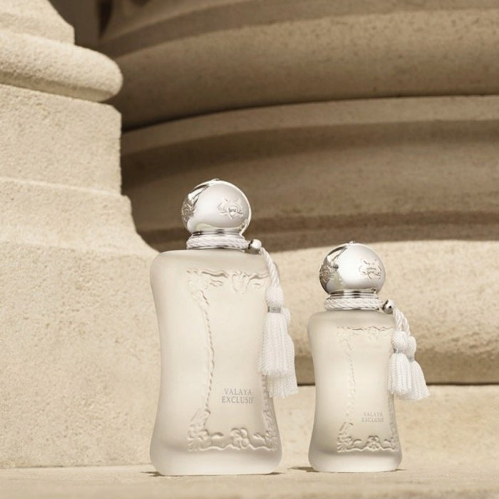 Parfums de Marly - Valaya Exclusif zeigt zwei matte Flakons mit verspieltem Quastenanhänger vor beige strukturiertem Hintergrund