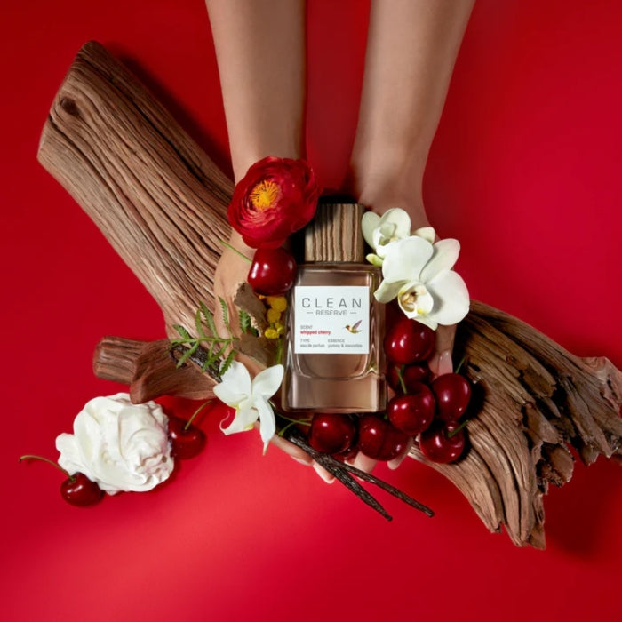 Clean Perfume - Reserve - Whipped Cherry Flakon mit Holzdeckel umgeben von Kirschen, Blumen und Holz auf rotem Hintergrund