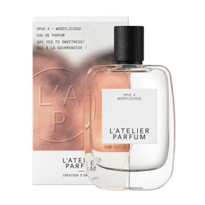 L'Atelier Parfum - Opus 4 - Woddylicious klarer Flakon mit schwarzem Holzverschluss vor kupferfarbener Verpackung