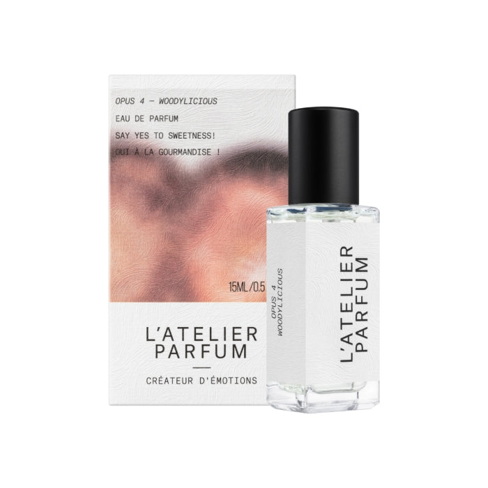 L'Atelier Parfum - Opus 4 - Woddylicious Parfumflakon mit schwarzem Deckel neben Verpackung in sanften Rosétönen