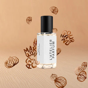 L'Atelier Parfum - Opus 4 - Woddylicious klarer Flakon mit schwarzem Deckel vor sandfarbenem Hintergrund mit Marron-Motiven