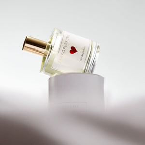 Zarkoperfume - Sending Love Parfumflakon mit goldenem Sprühkopf und rotem Herzsymbol auf hellem Hintergrund schwebend